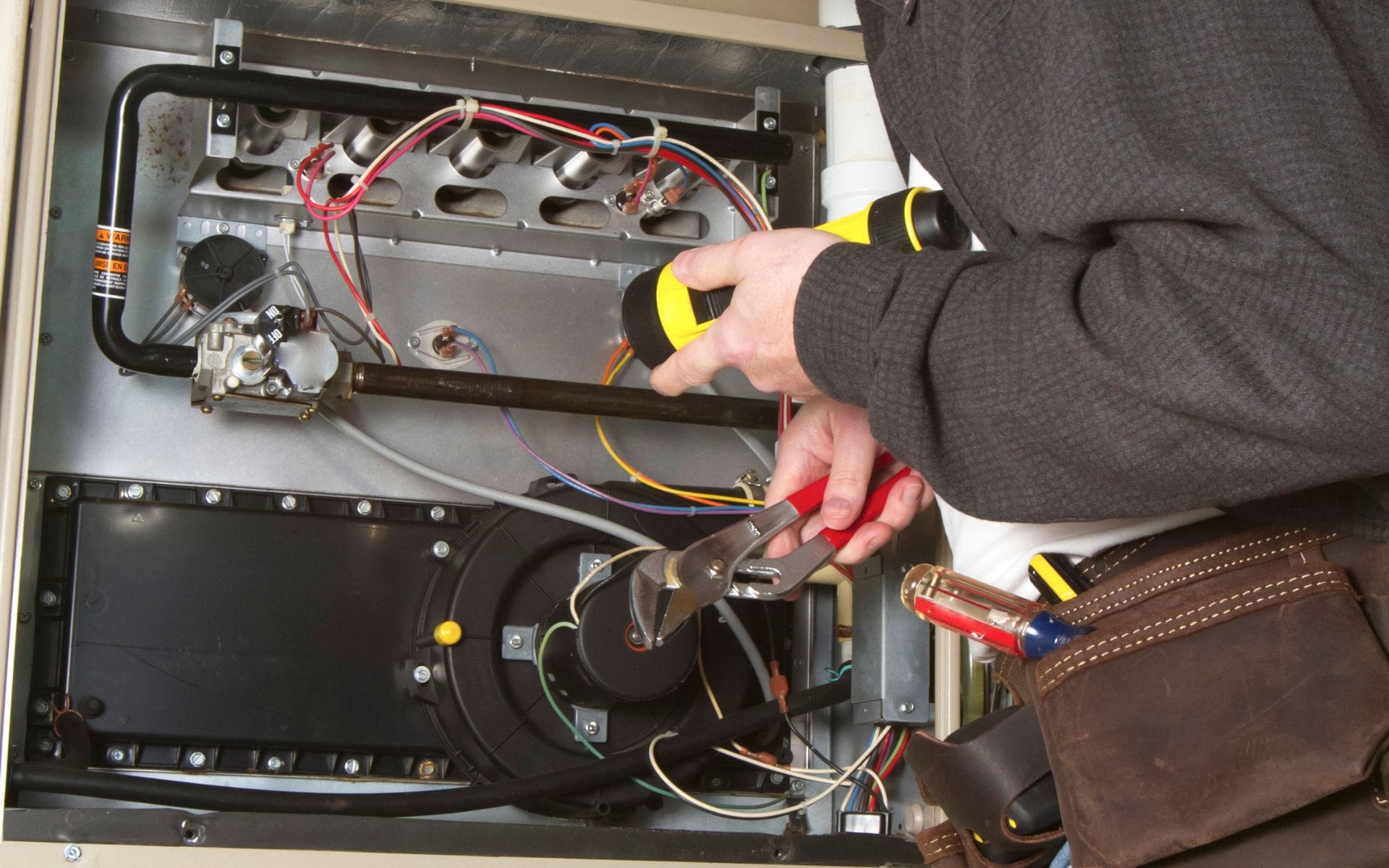 Technician repairing furnace wiring and components with tools