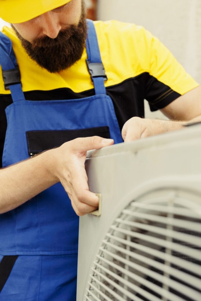 Close up of seasoned repairman installing condenser after replacing faulty unit. Adept worker commissioned to optimize air conditioner system performance, making sure it operates at maximum potential