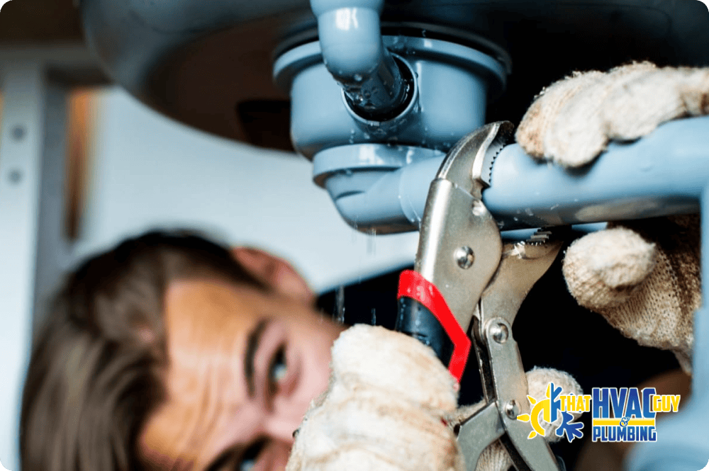Plumber repairing a leaking pipe joint with a wrench and sealing compound.