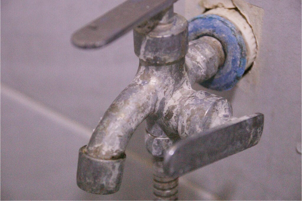 Water faucet heavily coated with mineral deposits, clearly showing issues caused by untreated hard water.